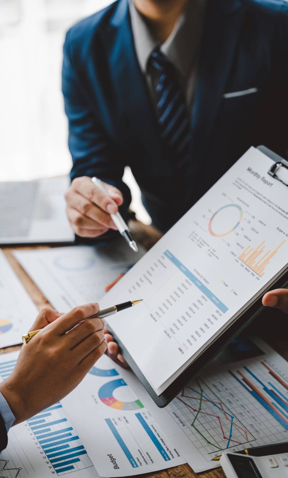 Young colleagues discuss business and analytical price charts using calculators and laptops to calculate financial, tax, accounting, statistics and analytical research ideas.